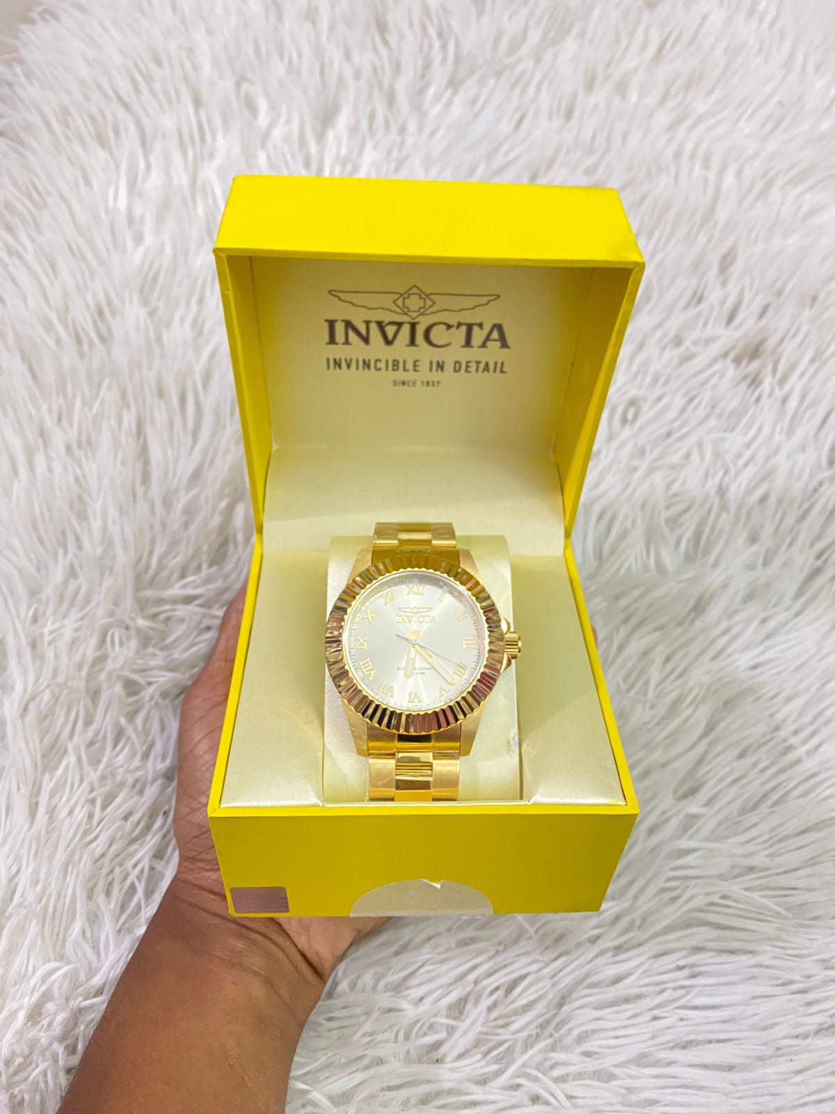 Reloj INVICTA original dorado con detalles en color blanco y letras INVICTA grabado en los lados.