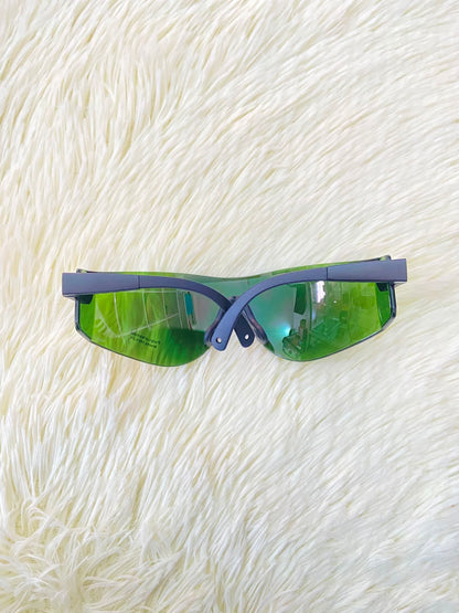Lentes, sin montura con micas en color verde y patillas negras.