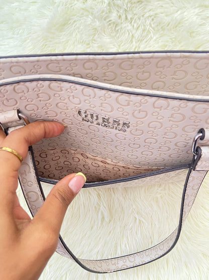 Cartera GUESS original, grande, rosado palo crema con letras G y placa GUESS en plateado en frente.