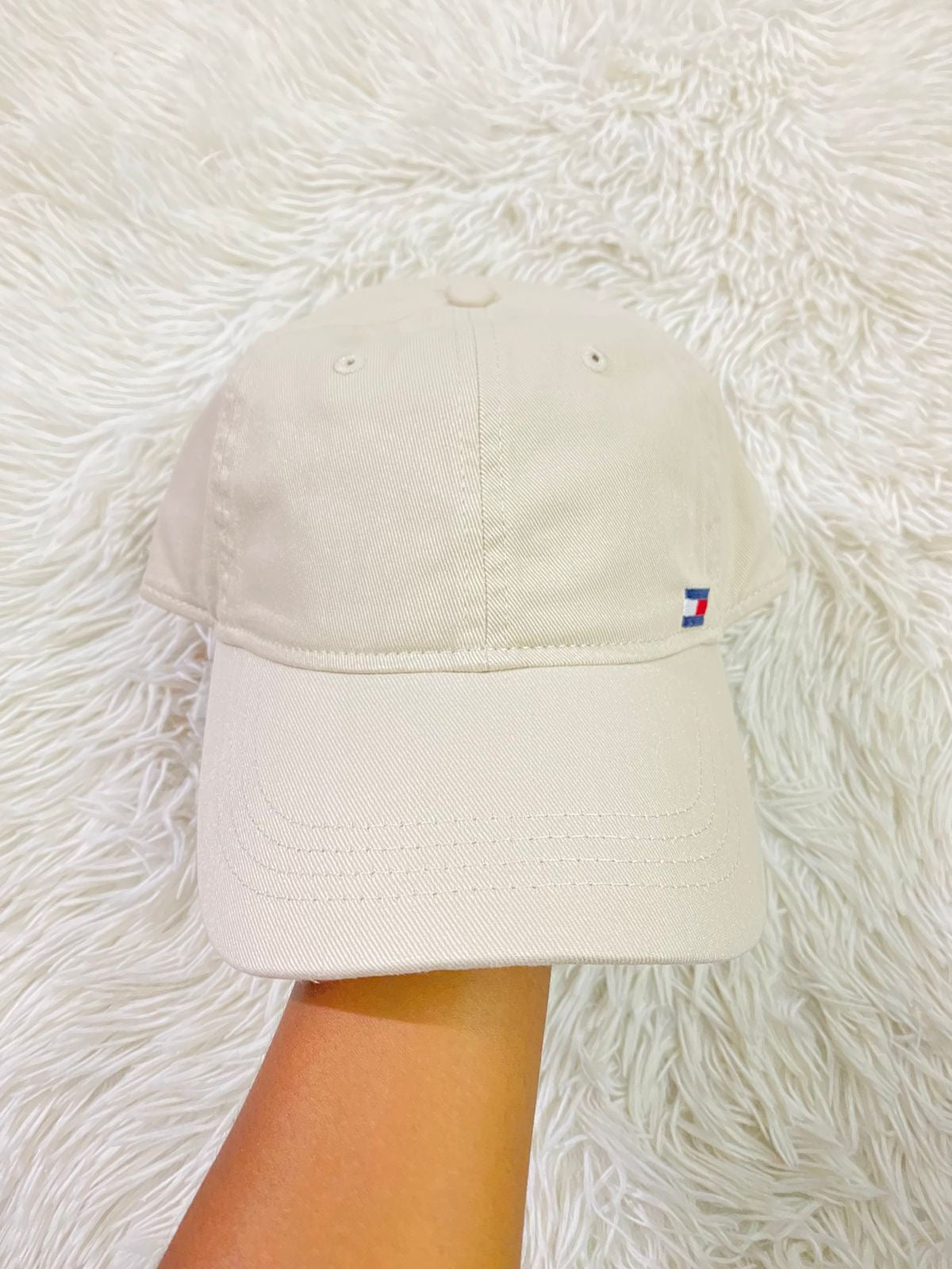 Gorra Tommy Hilfiger original crema con pequeño logotipo Tommy en la esquina y letras HILFIGER en azul.