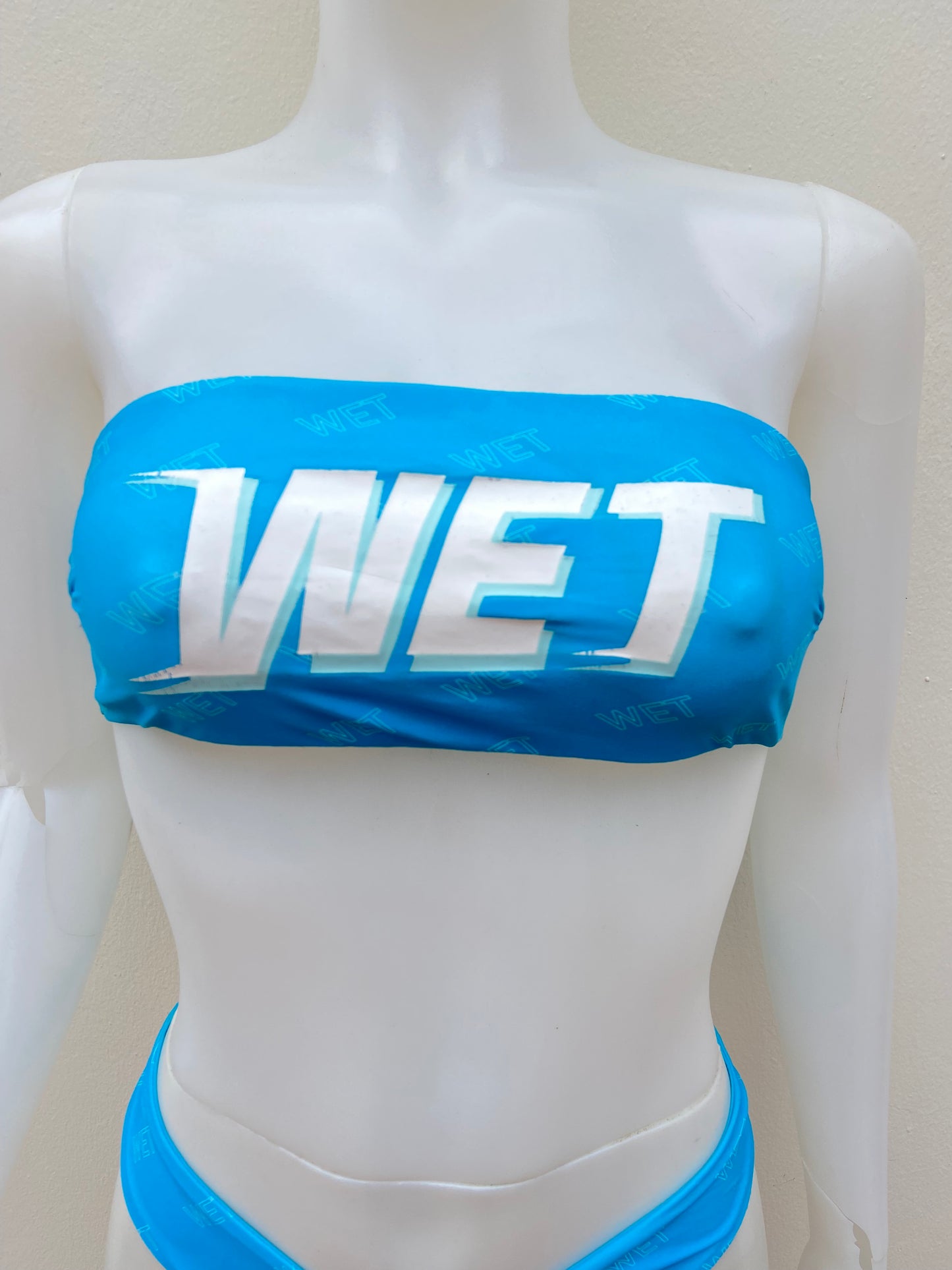Biquini, azul claro con letras WET en blanco, strapless, 2 piezas.