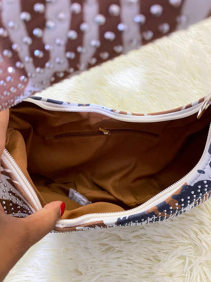 Cartera, color blanco con marron y estampado de animal print y detalles de piedras.