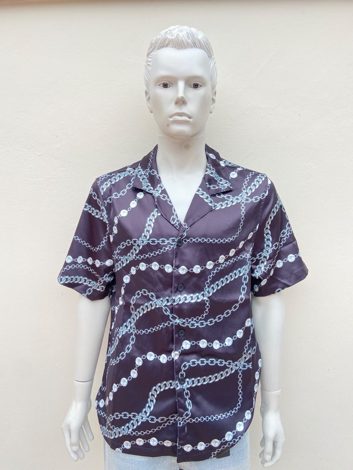 Camisa negra, con estampado de cadenas y perlas.