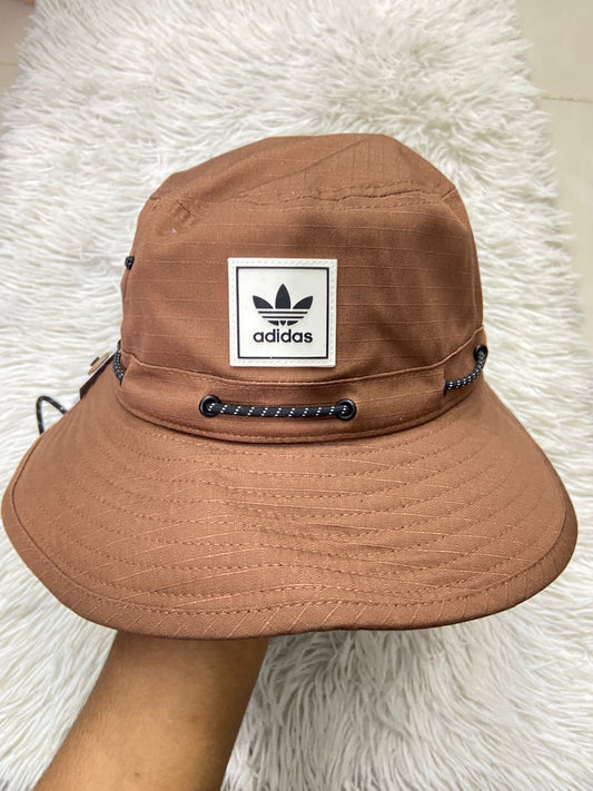 Gorro/Sombrero Adidas original marrón con lazo ajustable, con logotipo de la marca en frente.