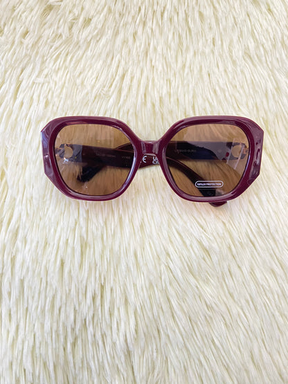 Lentes, rojo vino con micas oscuras y detalles dorado en los lados, con protección UV 100-400.