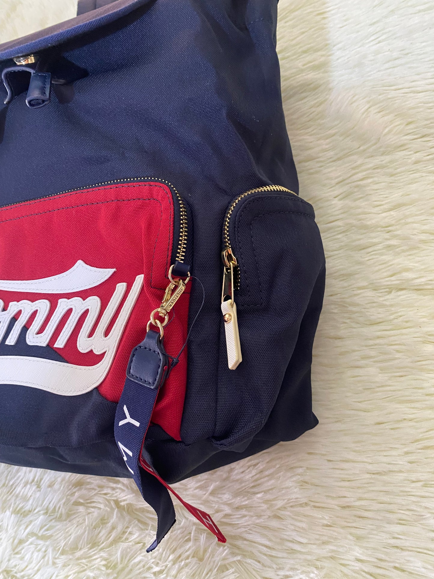 Mochila Tommy Hilfiger original en color azul marino, nombre TOMMY en grande en un bolsillo con el fondo rojo, varios compartimentos, súper espacioso.