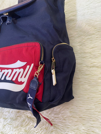 Mochila Tommy Hilfiger original en color azul marino, nombre TOMMY en grande en un bolsillo con el fondo rojo, varios compartimentos, súper espacioso.