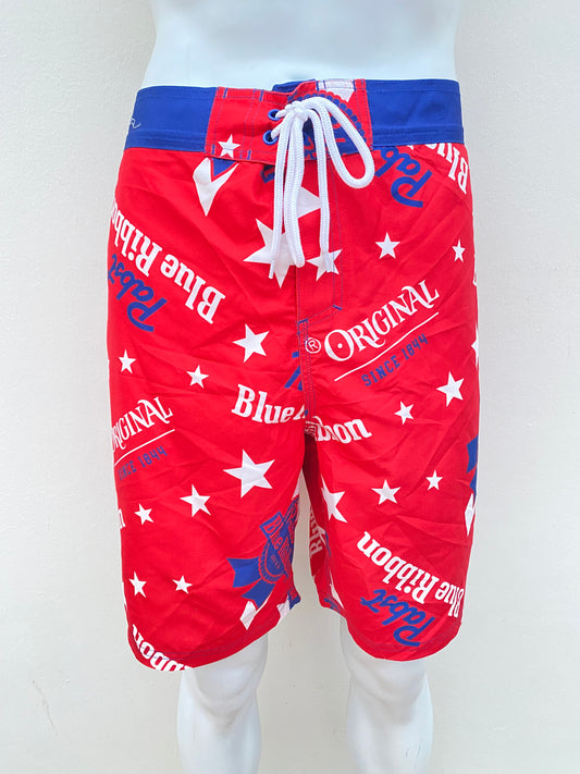 Bañador Baggy Nova Men original, roja con azul con diseños de estrellas en blanco y letras Pabst Blue Ribbon en azul.