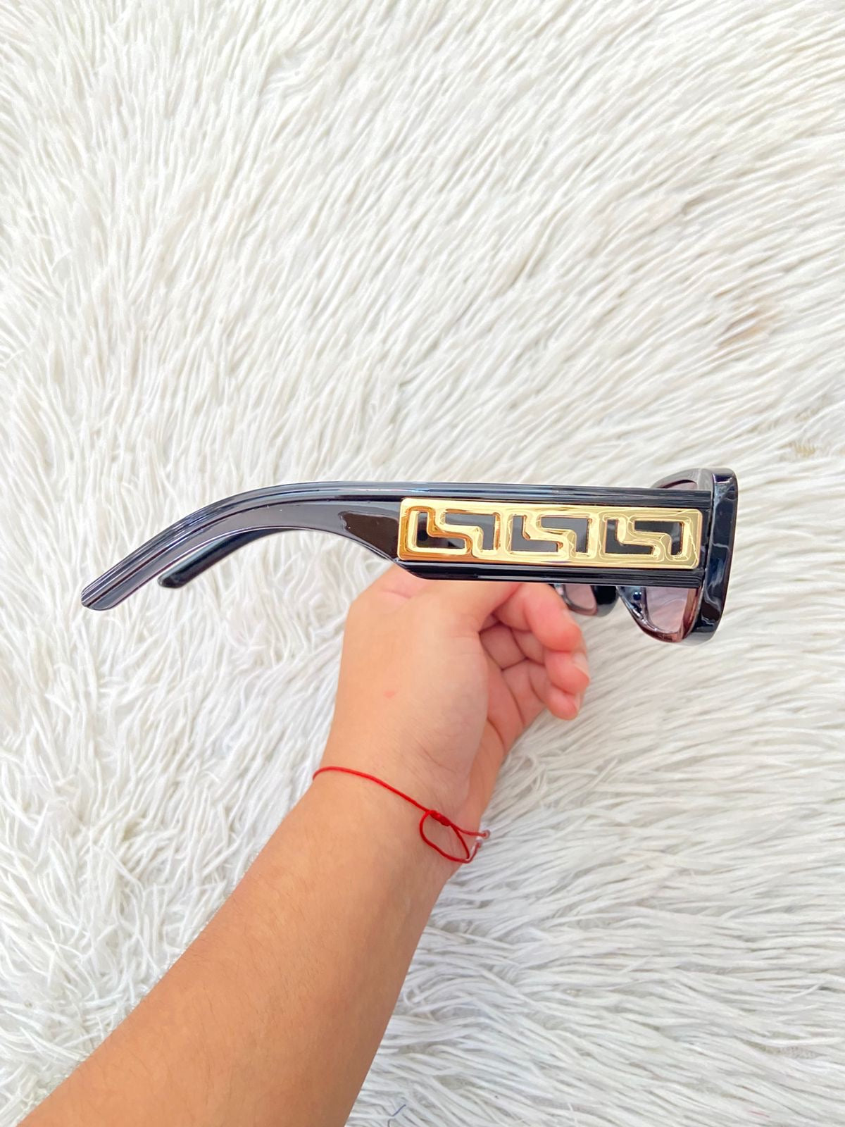 Lentes, negro con micas claras y montura en color negro y detalles en color dorado.