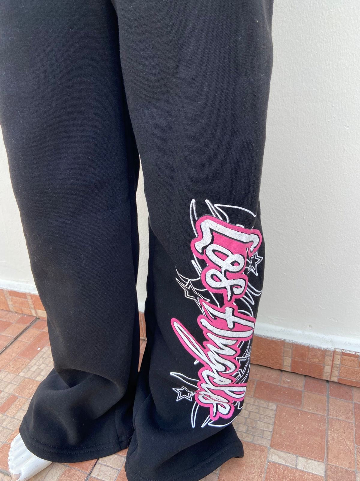 Jogger, negro liso con letras LOS ANGELES en rosado y blanco.