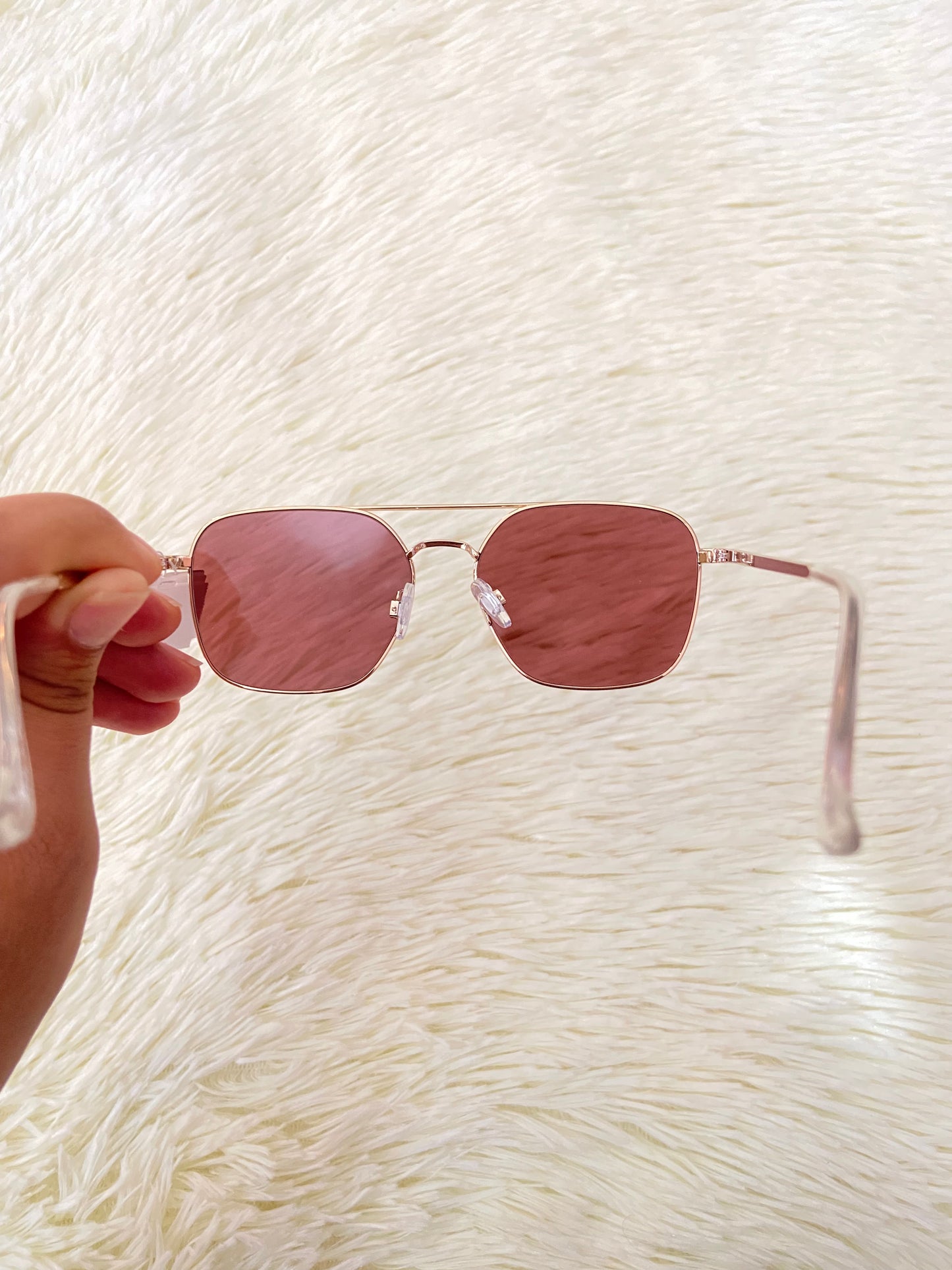Lentes con montura metálica delgada con tono dorado/rosado, micas rosadas.