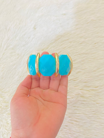Pulsera en color azul turquesa con detalles dorados.