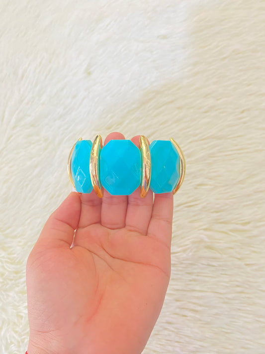 Pulsera en color azul turquesa con detalles dorados.