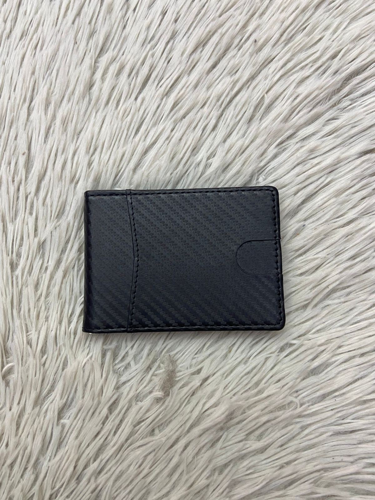 Billetera pequeña en color negra con clip para billetes, espacios para tarjetas y espacio transparente para cedula o licencia.