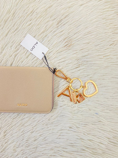Monedero/ Cartera ALDO Original en color crema con placa de la marca al frente en color dorado y llavero adicional.