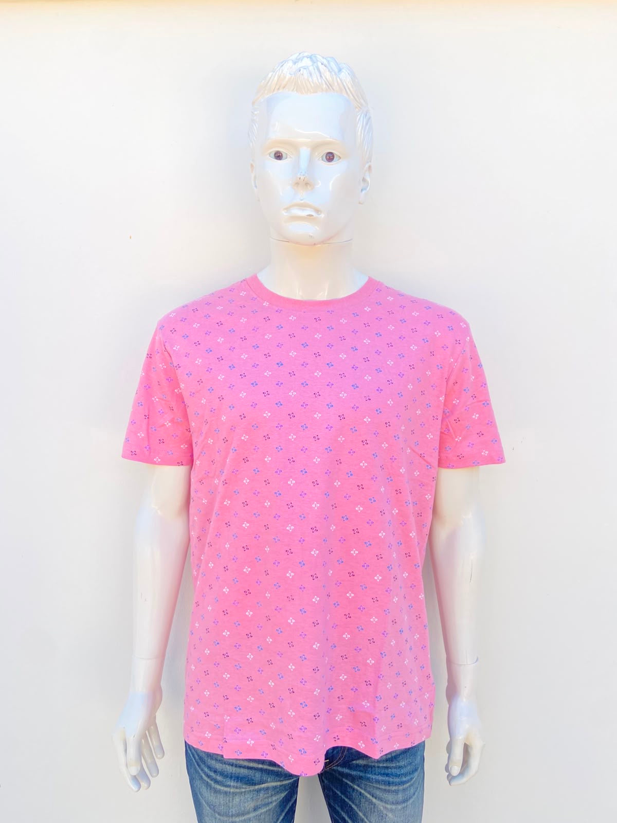 T-shirt MBX PREMIUM GOODS original, en color rosado claro con estampado de pequeñas figuras geométricas en color morado, azul negro y blanco, 100% algodón