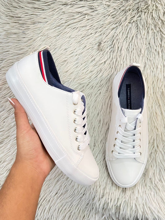 Tenis Tommy Hilfiger Original en color blanco con banda en color azul marino blanco y rojo en la parte trasera y placa de la marca atras. TH