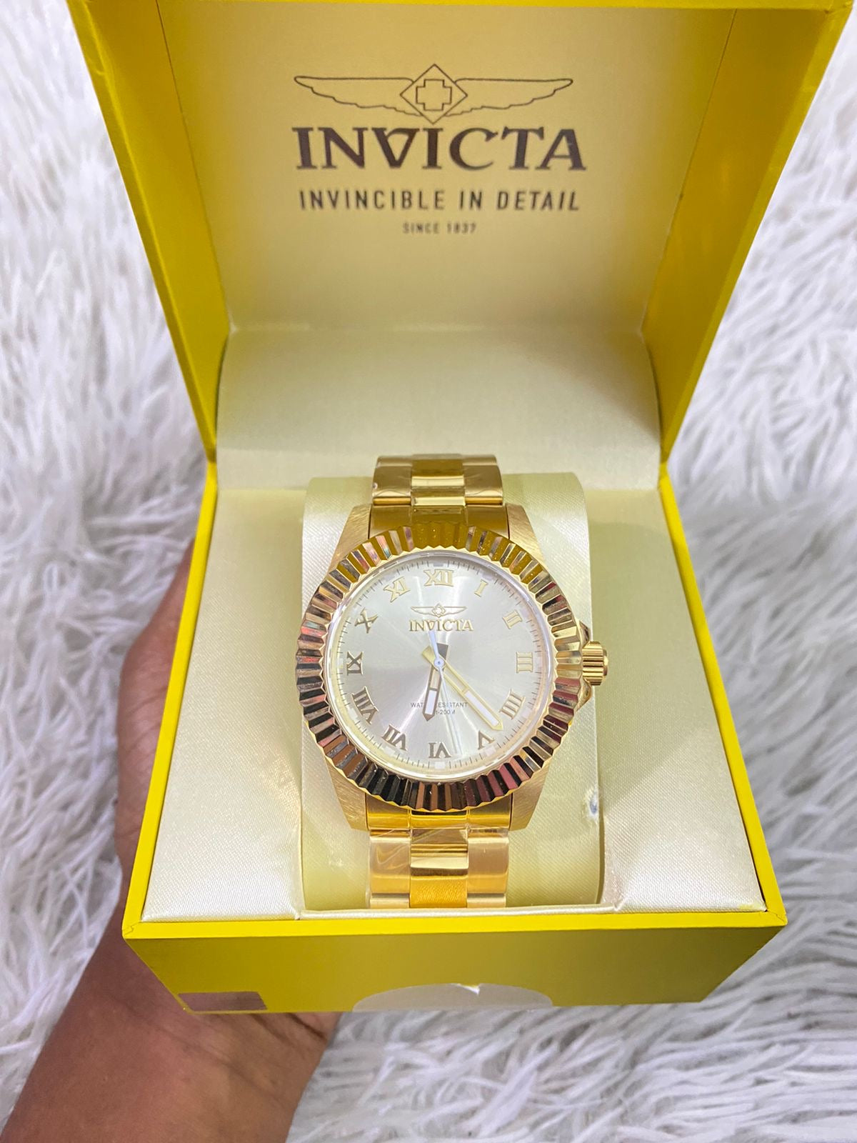 Reloj INVICTA original dorado con detalles en color blanco y letras INVICTA grabado en los lados.