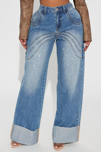 Pantalon jean azul con deslavado medio, detalle de algunas salpicaduras en color blanco, costuras decorativas alante y atras y doblado abajo.