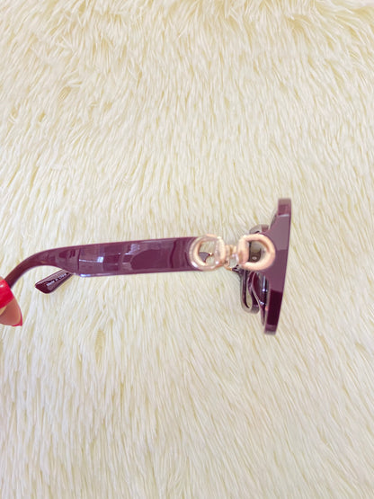 Lentes, rojo vino con micas oscuras y detalles dorado en los lados, con protección UV 100-400.