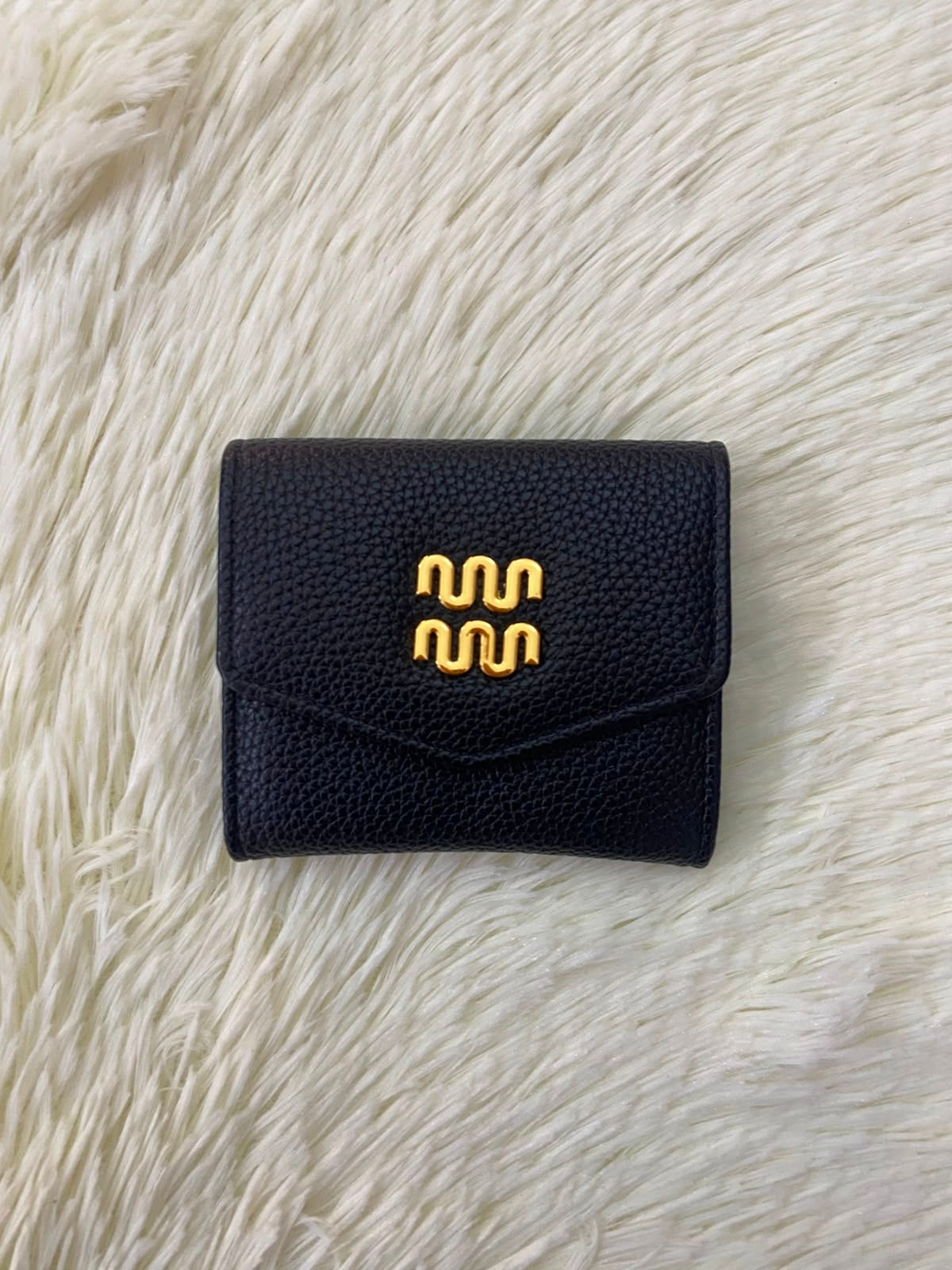 Monedero pequeño negro con diseño al frente en color dorado, cierre de boton y súper espacioso.