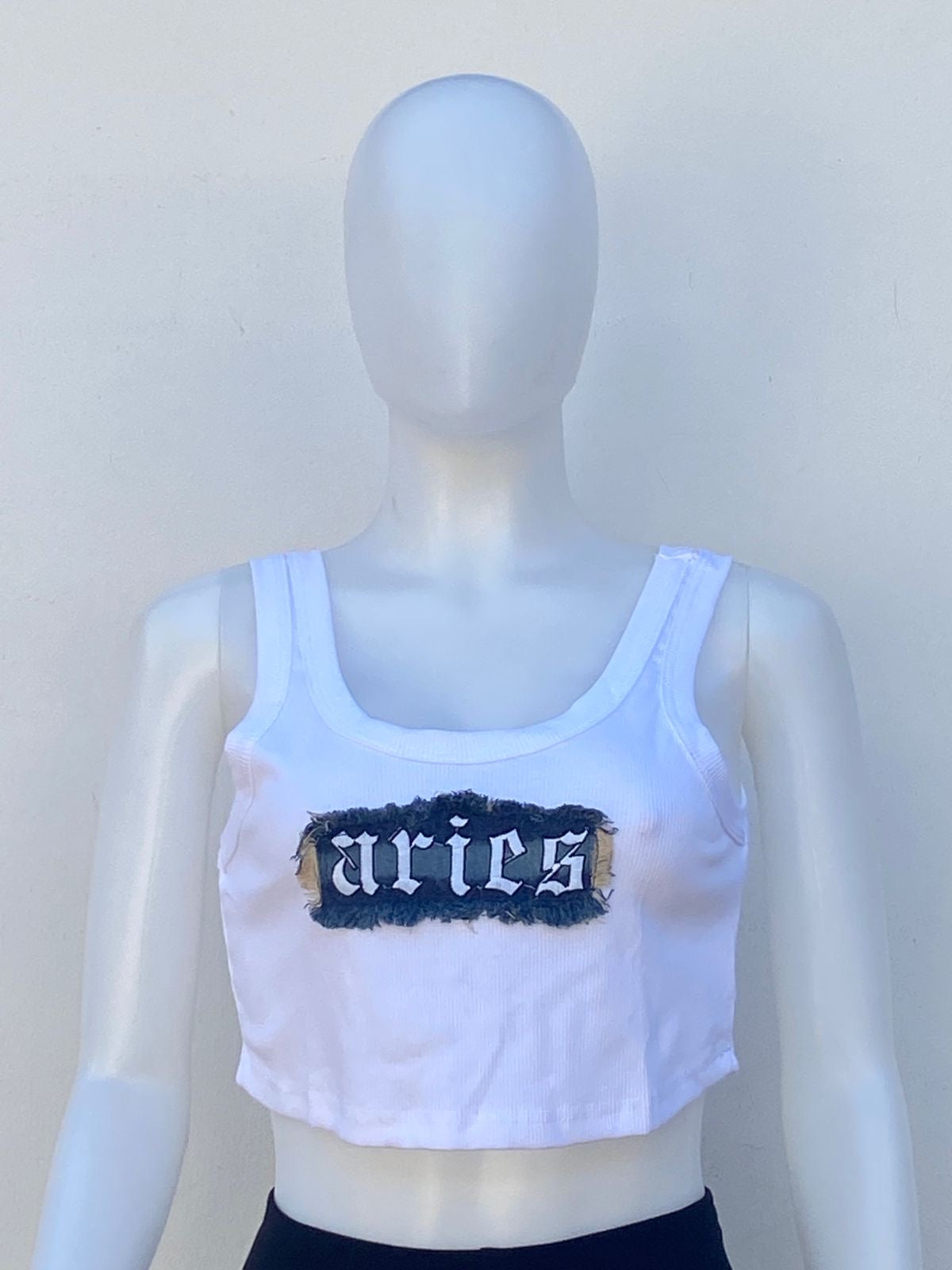 Top, blanco con letras ARIES en Jean azul oscuro.