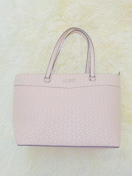 Cartera GUESS original, grande, rosado palo crema con letras G y placa GUESS en plateado en frente.
