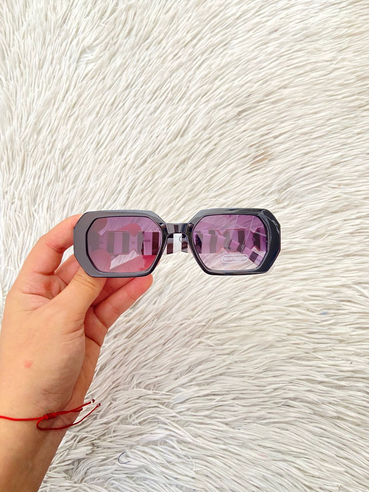 Lentes, negro con micas en color morado/ negro oscuro y montura con rayas blancas y negra y detalles en color dorado.