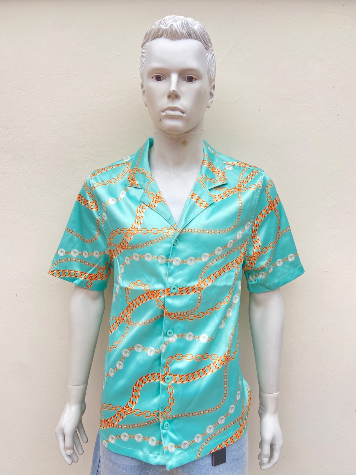 Camisa azul turquesa, con estampado de cadenas y perlas.