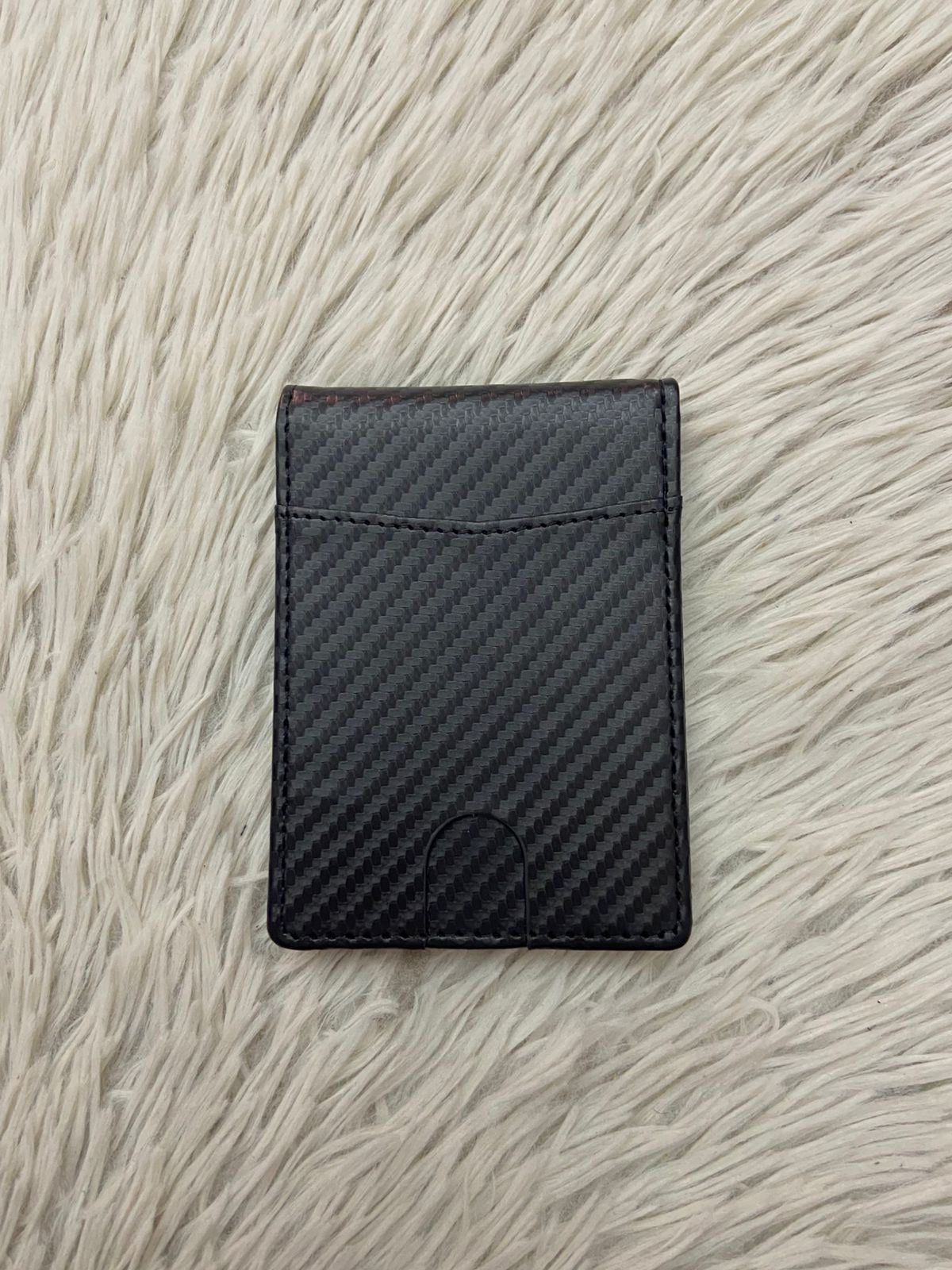 Billetera pequeña en color negra con clip para billetes, espacios para tarjetas y espacio transparente para cedula o licencia.