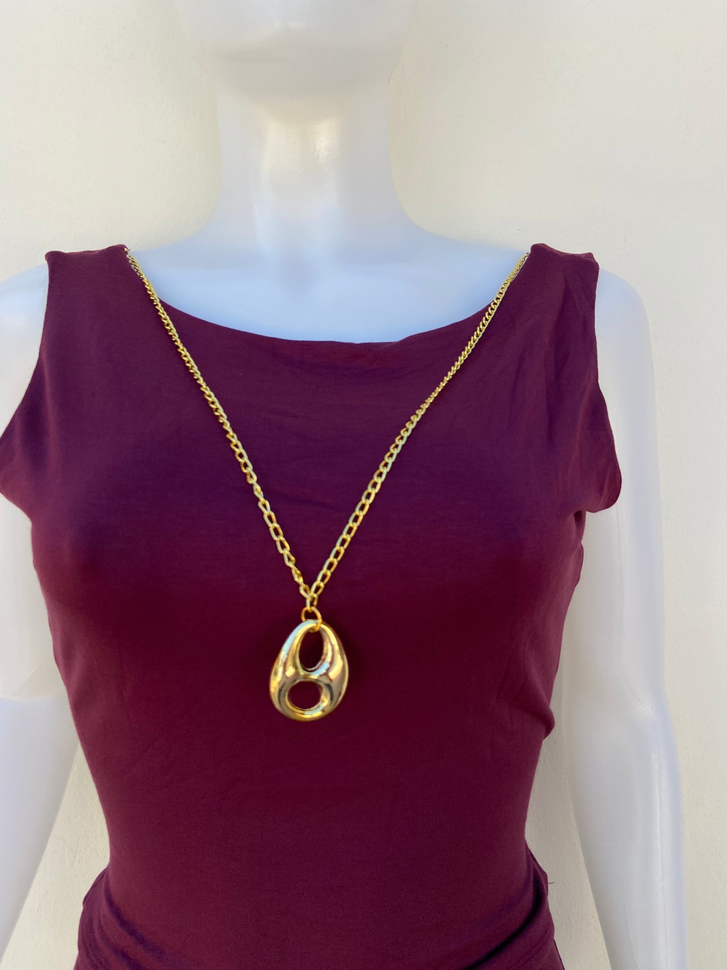 Conjunto, rojo vino de pantalon y top con Cadena colgante  en dorado en frente y escote en la espalda.