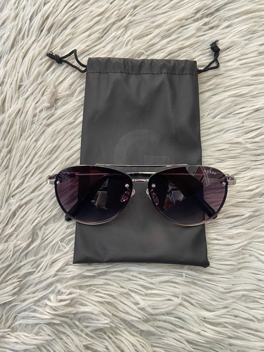 Lentes GUESS Original con marco plateado, letra guess al frente, micas grandes y con degradado morado oscuro.