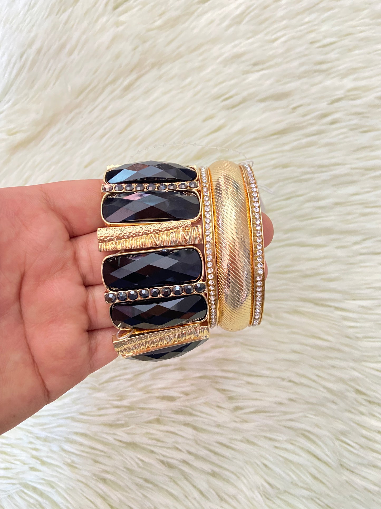 Set de pulseras una en color dorado con detalles plateados y otra con Piedras grandes negras y doradas.