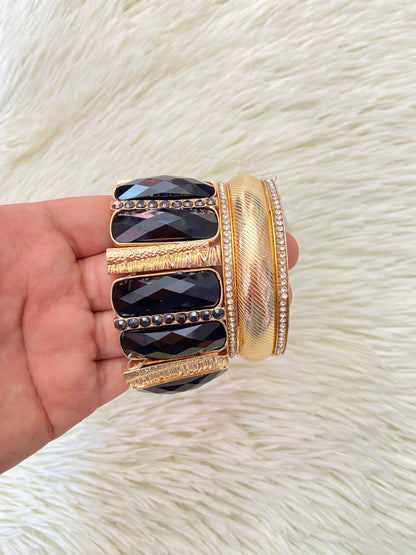 Set de pulseras una en color dorado con detalles plateados y otra con Piedras grandes negras y doradas.