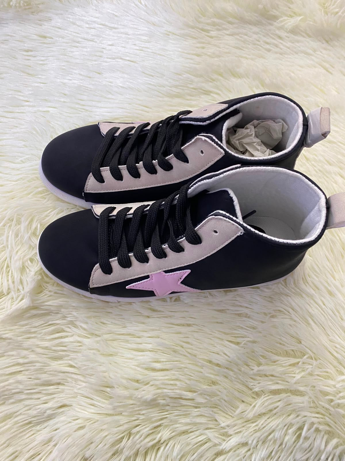 Tenis, negro con suelas en color blanco y estampado de estrella en color rosado al lado.