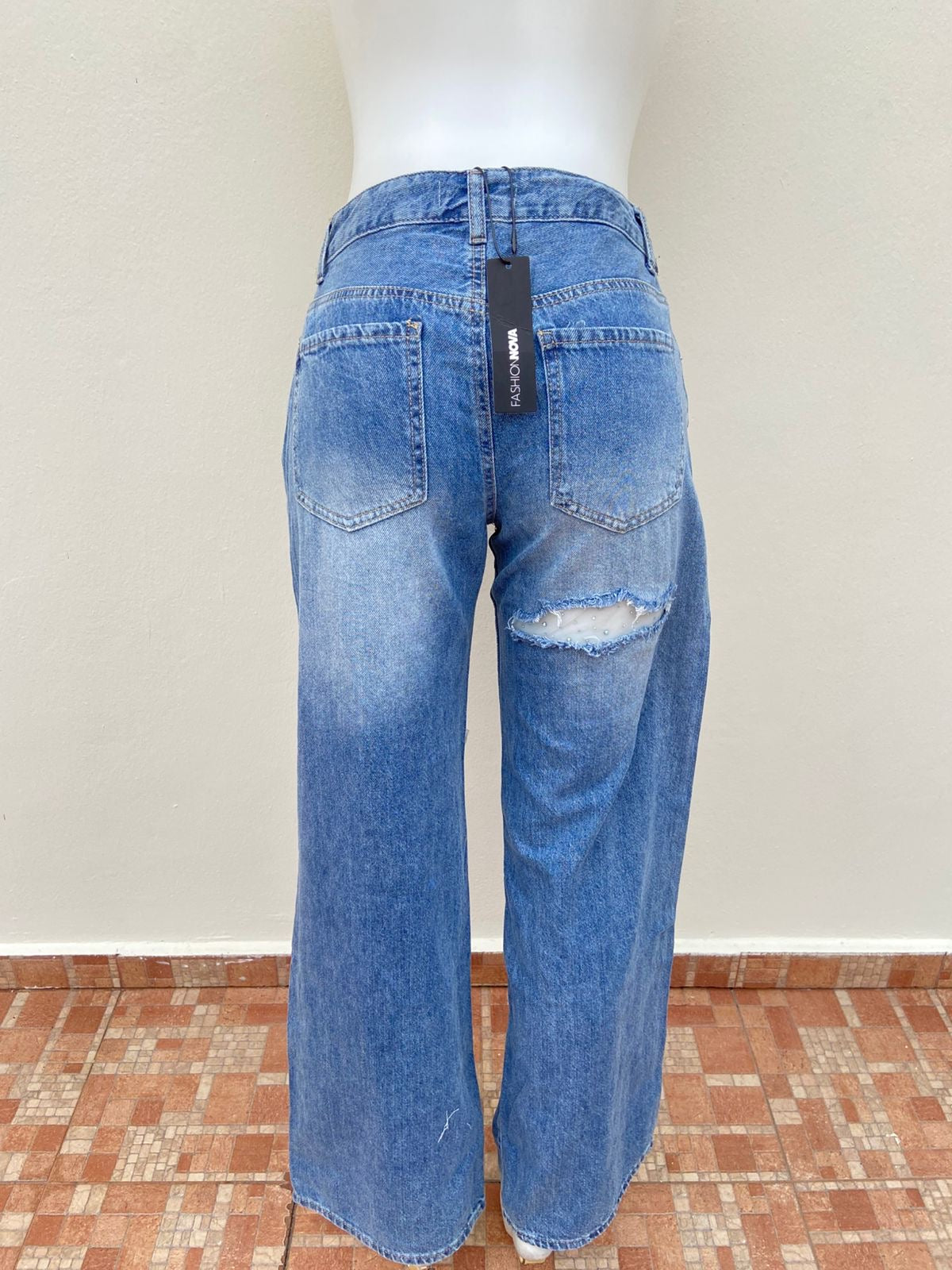 Pantalón Jean, azul con varios rasgados y malla transparente con brillos en los rotos.