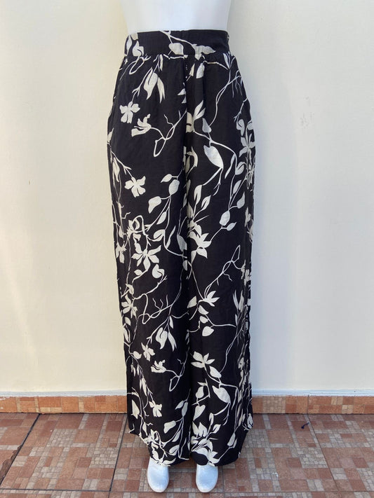Pantalon negro con estampados de flores blancas estilo, en tela estilo palazzo.