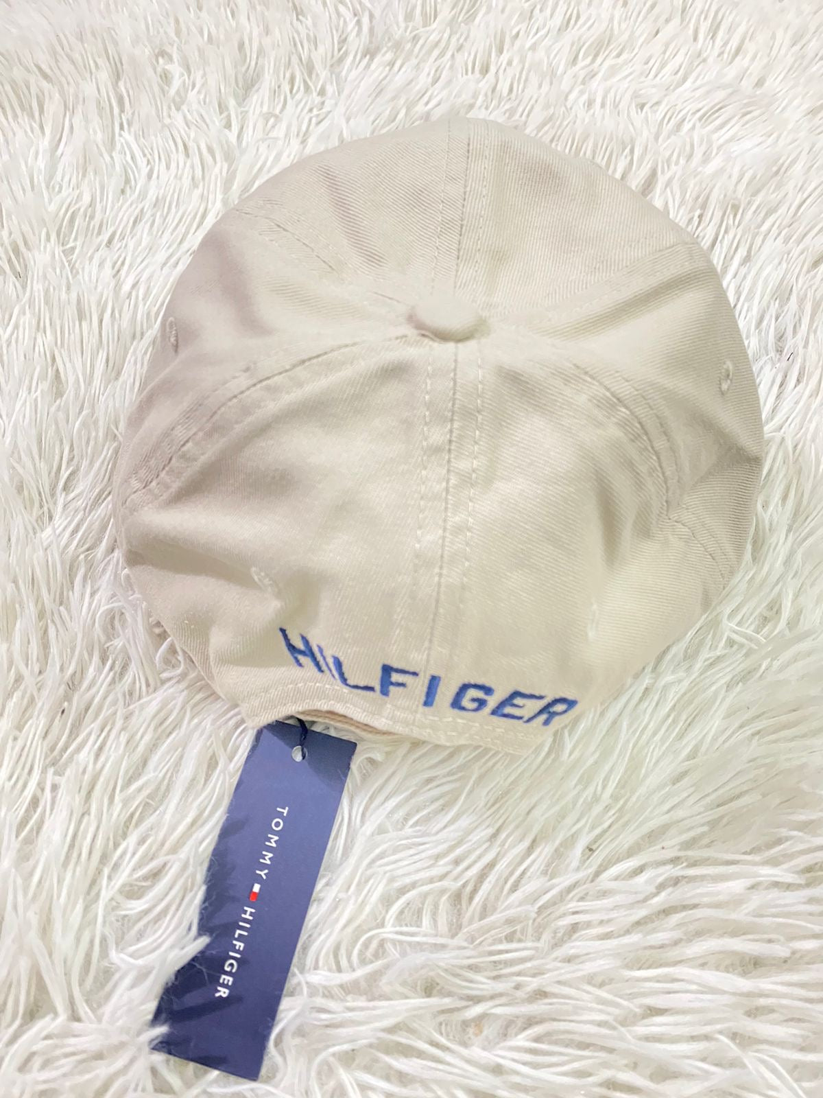 Gorra Tommy Hilfiger original crema con pequeño logotipo Tommy en la esquina y letras HILFIGER en azul.