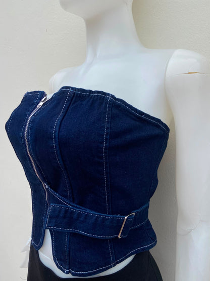 Top jean azul, con zíper al frente y detalle de lazo ajustable.