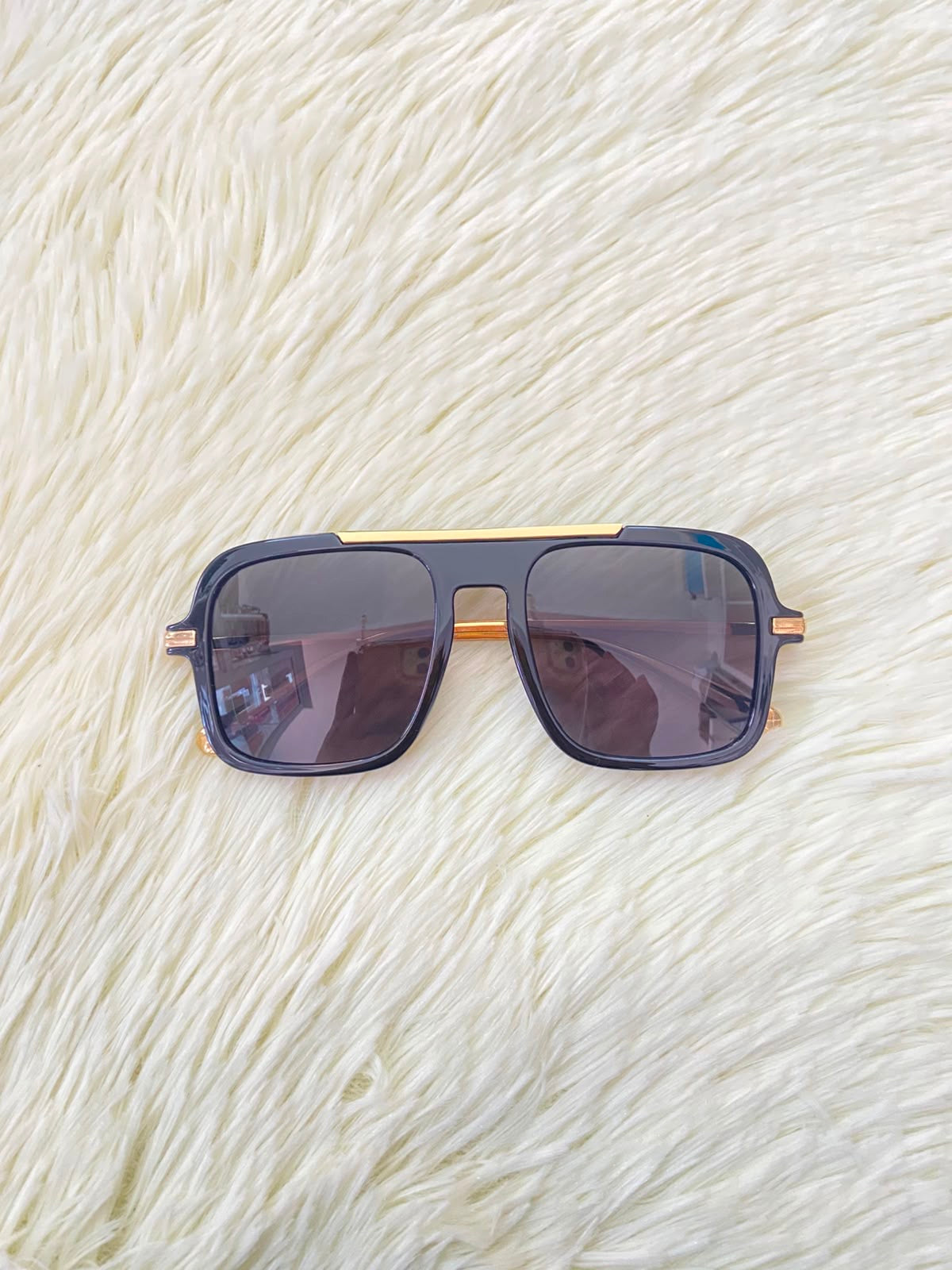 Lentes, negros con detalle dorado al frente y patillas doradas.