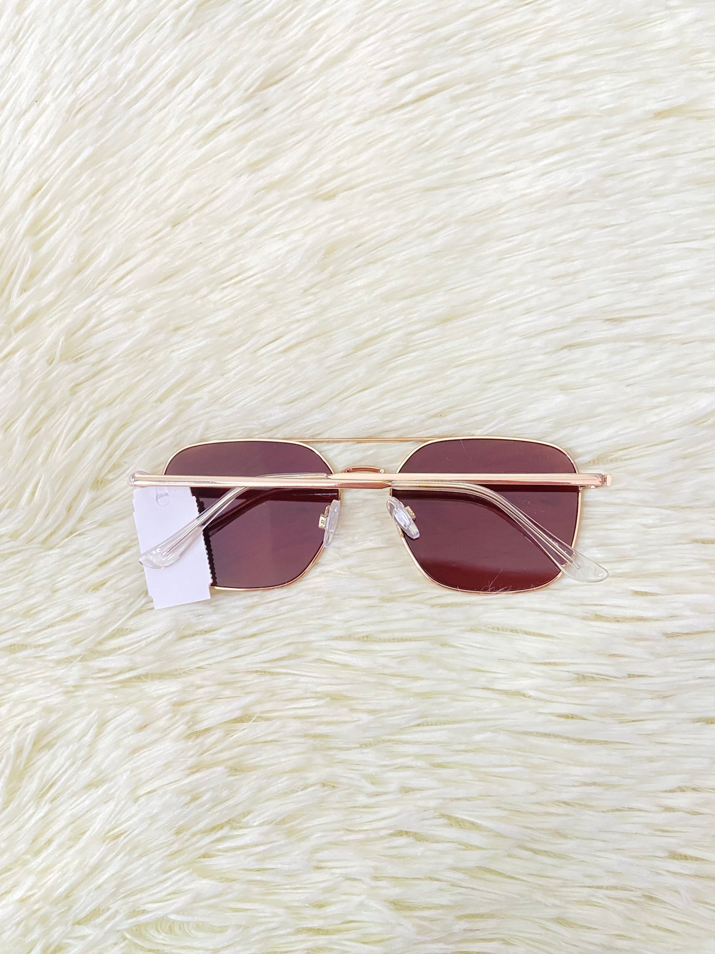 Lentes con montura metálica delgada con tono dorado/rosado, micas rosadas.