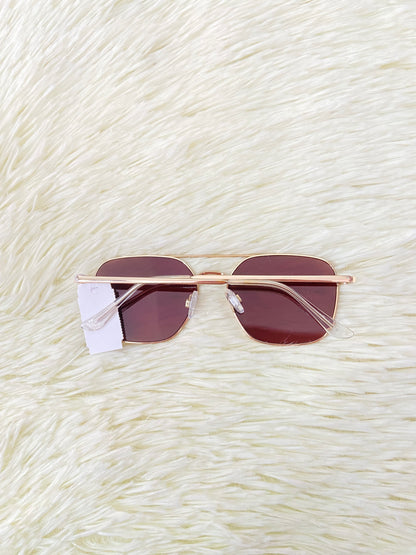 Lentes con montura metálica delgada con tono dorado/rosado, micas rosadas.