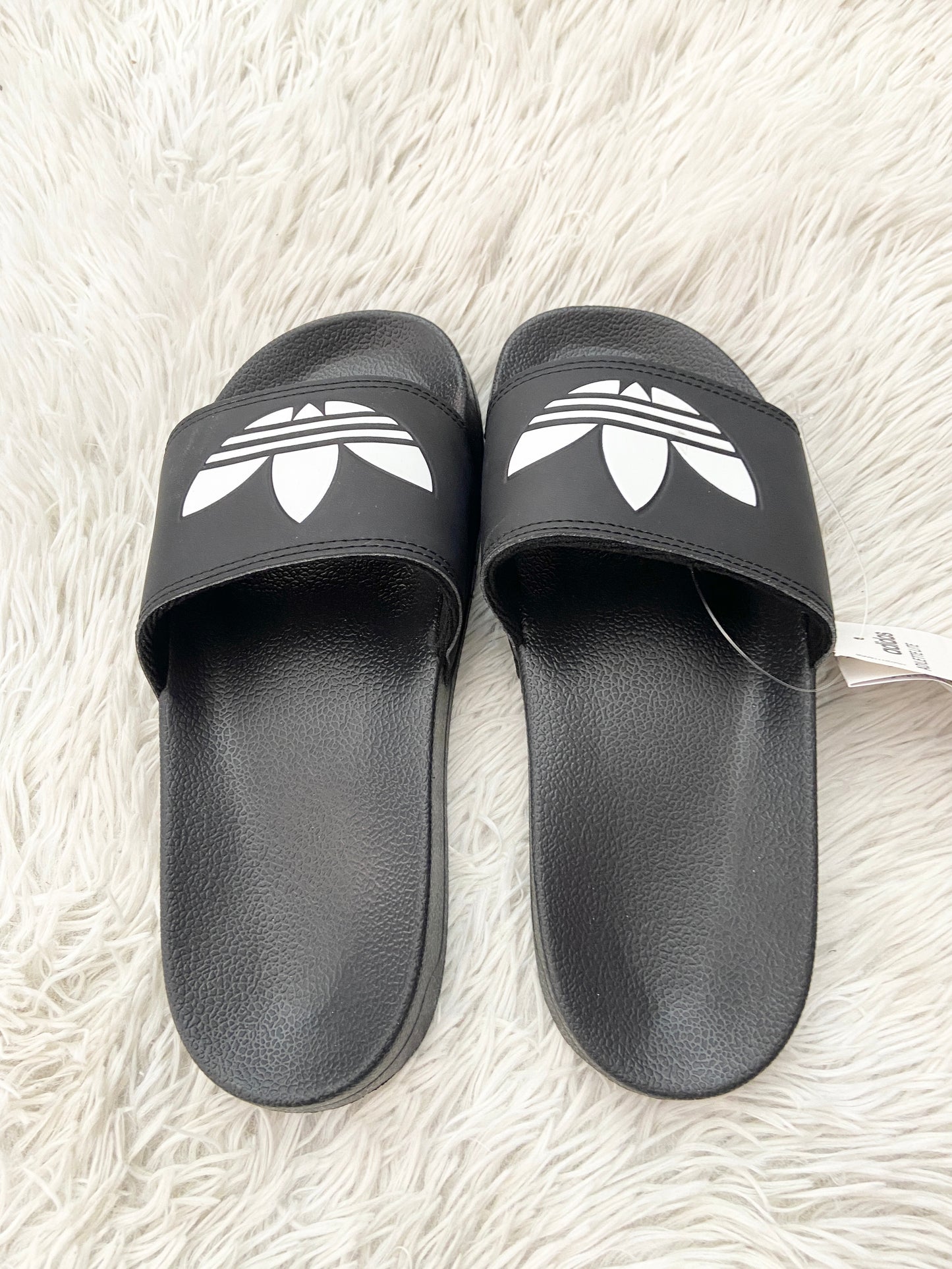 Sandalias Adidas original negra con logotipo en frente de la marca en blanco.