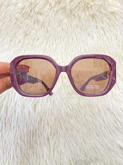 Lentes, rojo vino con micas oscuras y detalles dorado en los lados, con protección UV 100-400.