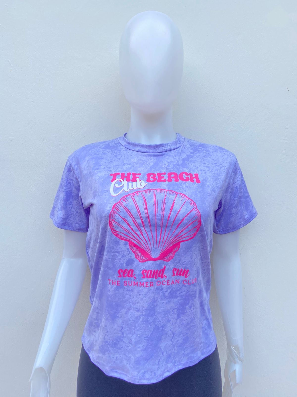 T-shirt, morado lila con blaco y estampado de una concha marina en color rosa y letras THE BEACH CLUB.