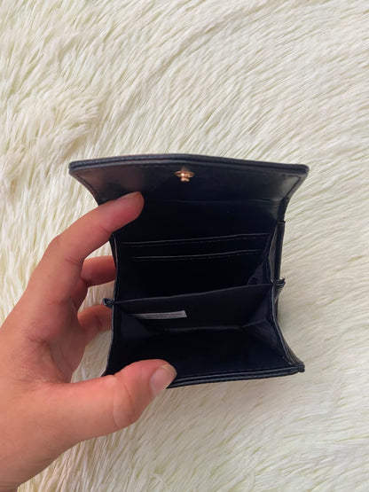 Monedero pequeño negro con diseño al frente en color dorado, cierre de boton y súper espacioso.