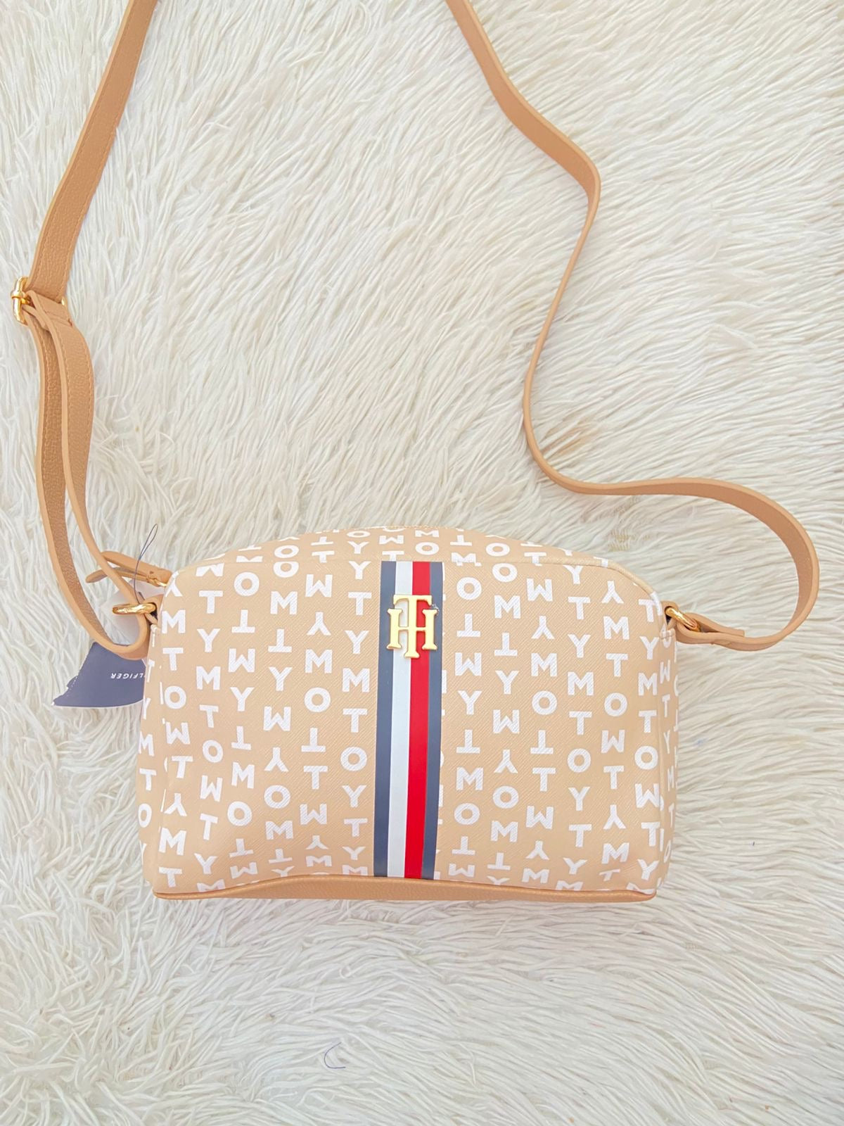 Cartera TOMMY HILFIGER original crema con estampado de letras TOMMY y banda de color rojo, azul y blanco y placa TH en dorado.