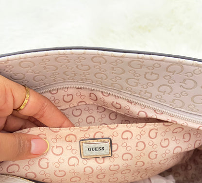 Cartera GUESS original, grande, rosado palo crema con letras G y placa GUESS en plateado en frente.