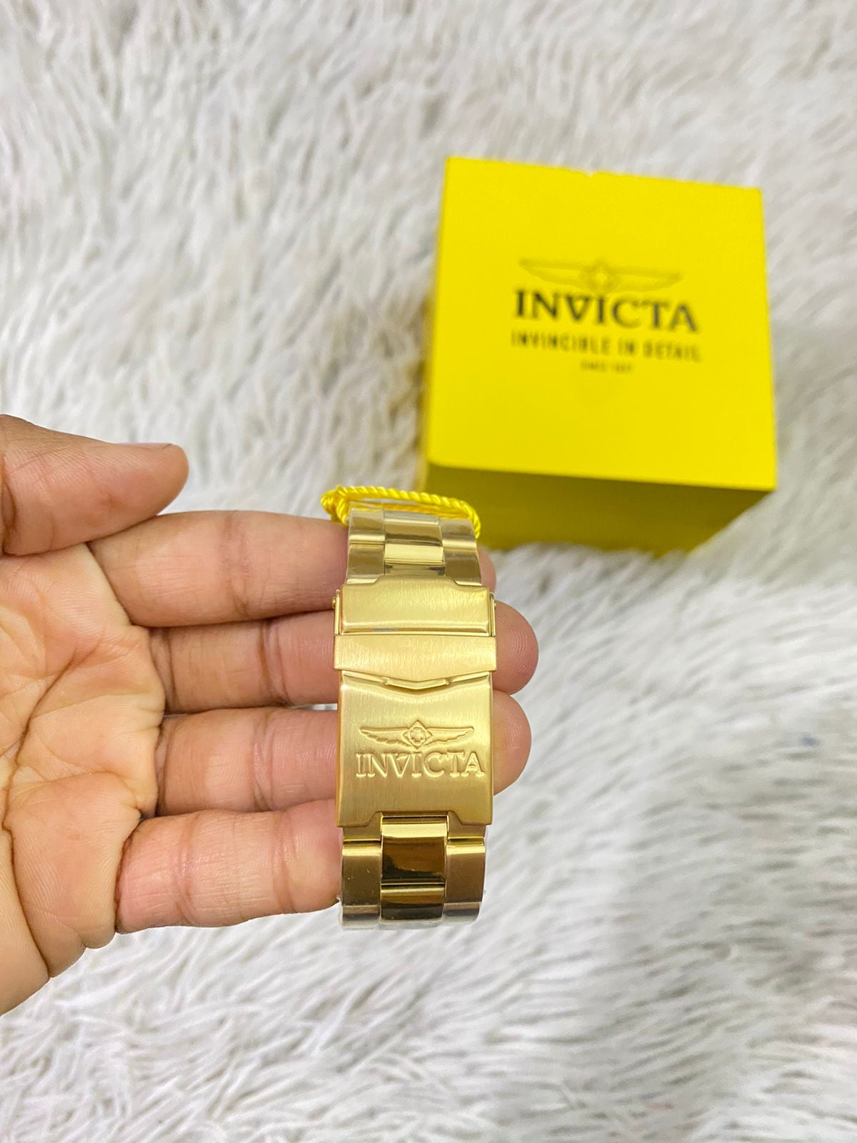 Reloj INVICTA original dorado con detalles en color blanco y letras INVICTA grabado en los lados.