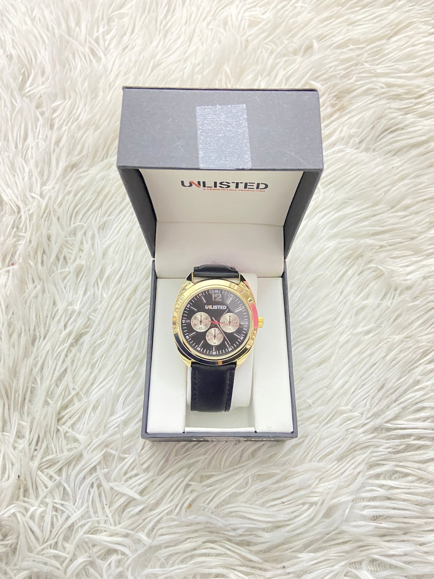 Reloj UNLISTED KENNETH COLE original negro con detalles en color dorado.